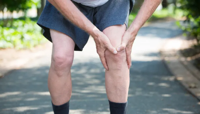 Runner clutching his knee in pain while out on a jog