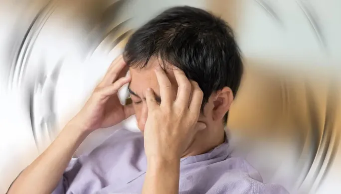 Man holding his head with a blurred, spinning room effect suggesting vertigo