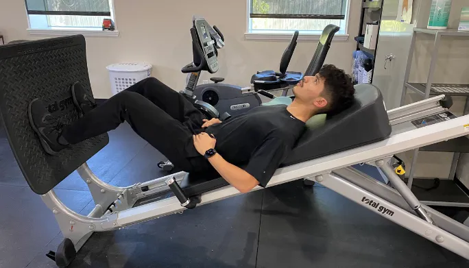 Man using leg-press exercise equipment in the clinic gym