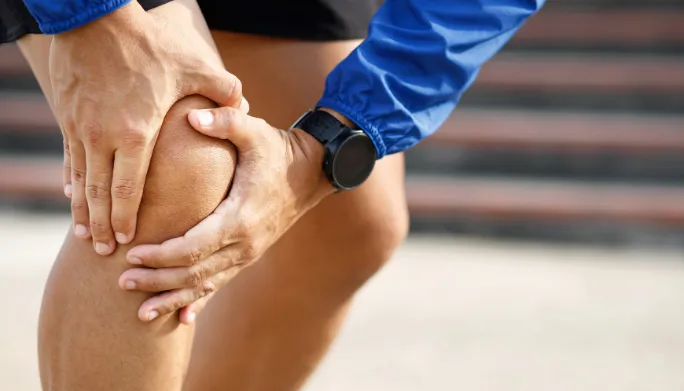 Person holding their knee in pain during a run
