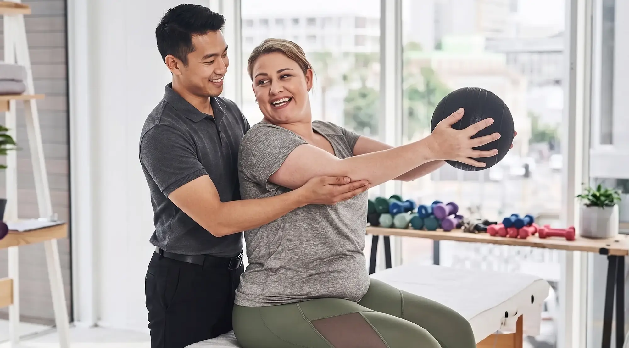 Physical therapist guiding a patient through a seated medicine-ball rotation exercise