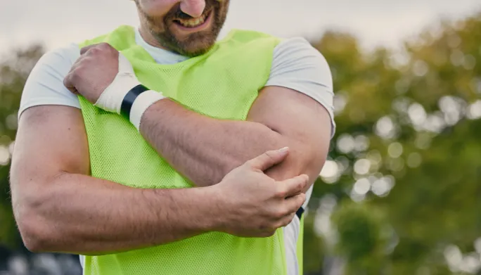 Athlete outdoors holding his elbow in pain